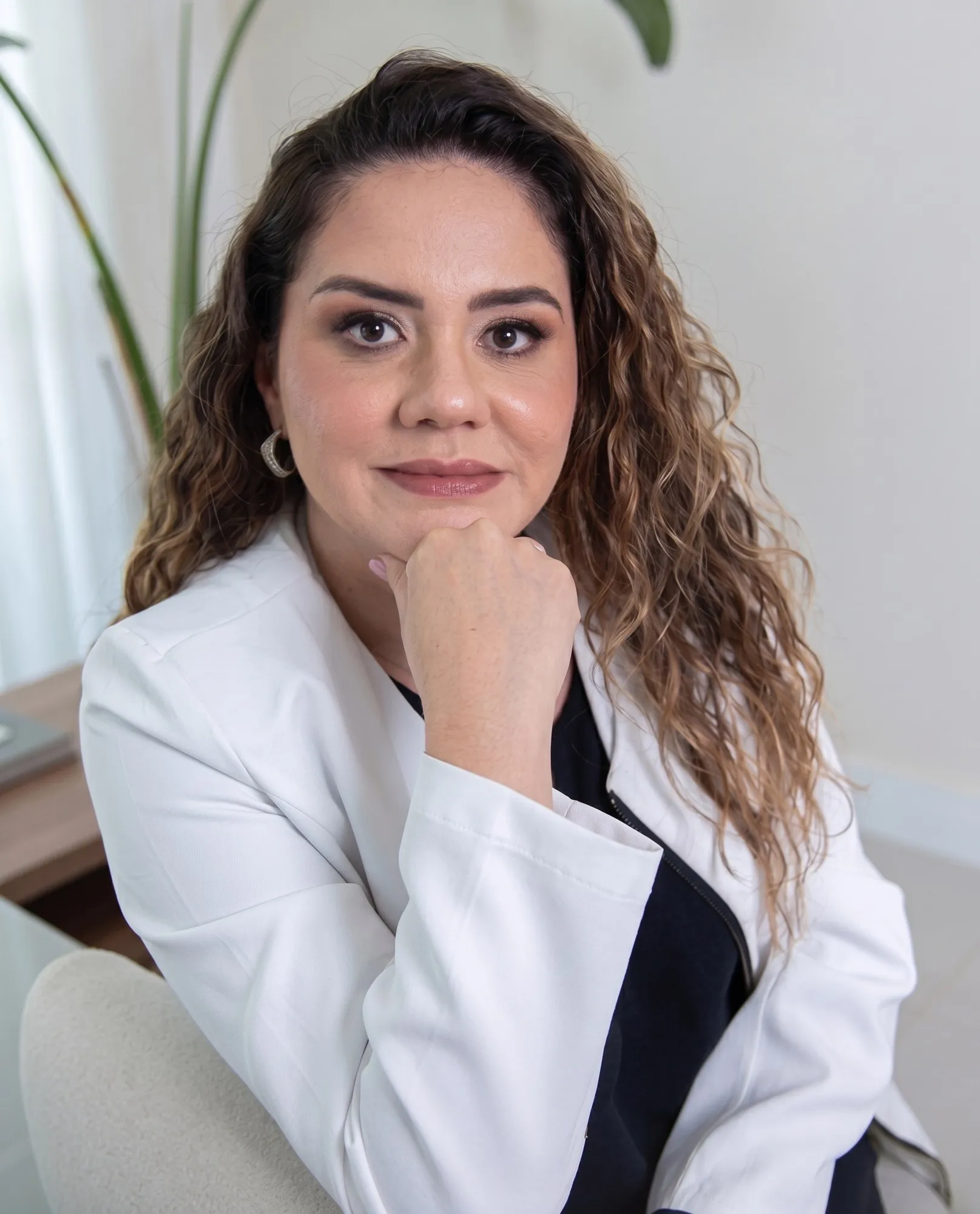 Dra. Gigliola Peláez, médica pediatra, de jaleco branco, sorrindo em seu consultório